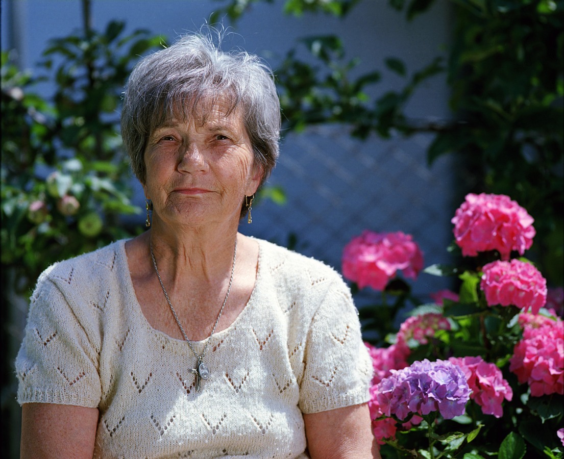 elderly woman in front of flowers